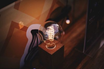 Close-up of illuminated light bulb on table