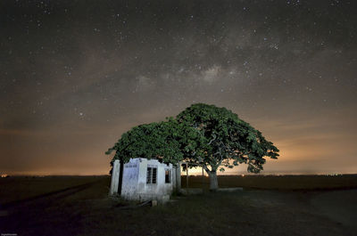 Old house by tree against sky at night