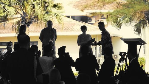 Silhouette people standing by palm tree