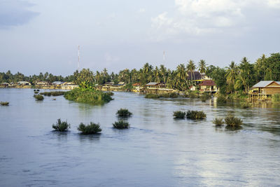 Scenic view of river by buildings against sky