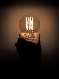 Person holding light bulb against black background