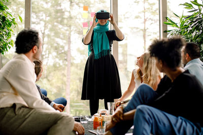 Businesswoman smiling while wearing virtual reality simulator during conference with colleagues at convention center