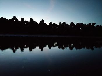 Silhouette trees by lake against sky