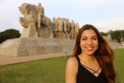 Portrait of smiling young woman against sky