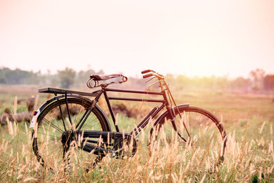 Damaged bicycle on field against sky