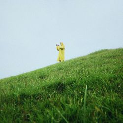 Rear view of woman standing on grassy field against clear sky