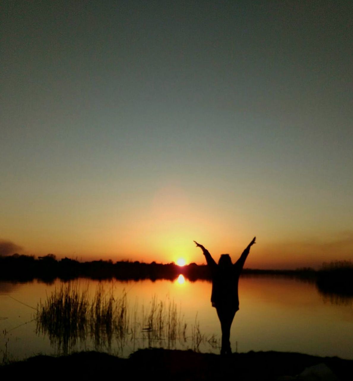 sunset, silhouette, sky, human arm, beauty in nature, standing, tranquility, one person, scenics - nature, orange color, tranquil scene, real people, leisure activity, arms raised, nature, limb, lifestyles, non-urban scene, water, copy space