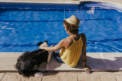 Rear view of woman sitting by swimming pool