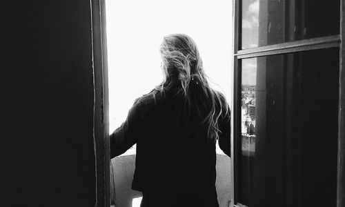 Rear view of woman looking through window