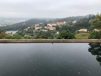 Scenic view of river by buildings against sky