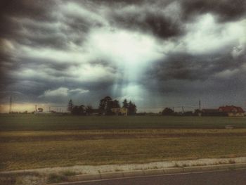 Scenic view of field against storm clouds