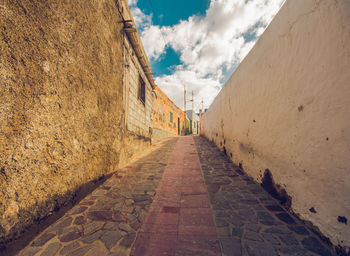 Narrow alley amidst buildings against sky