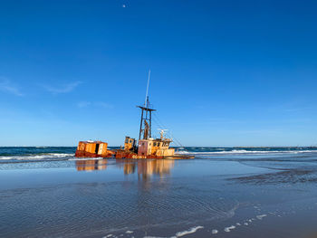 Sailboat on beach against blue sky