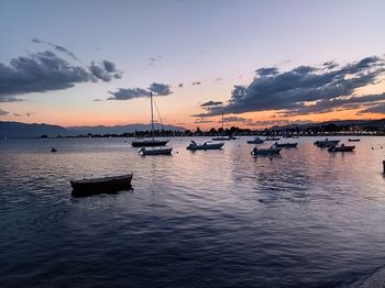 Sailboats moored in marina at sunset