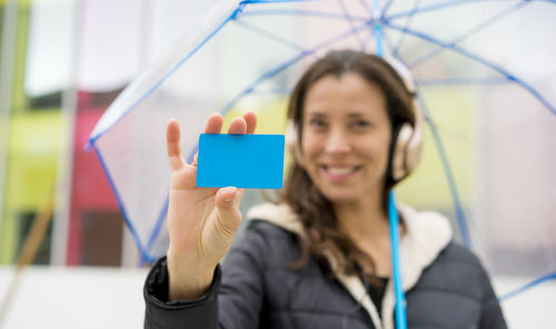 Woman showing business card while holding umbrella