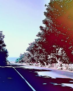 Road amidst trees against clear sky