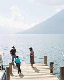 People on sea shore against mountains