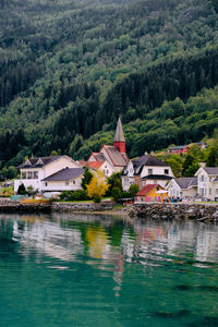 Houses by lake and buildings against trees