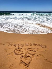 Text on sand at beach against sky