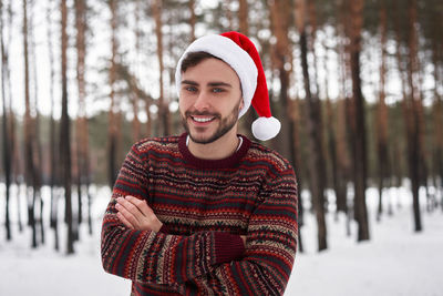Portrait of smiling young man standing in snow