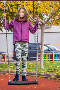 Girl standing on swing in playground