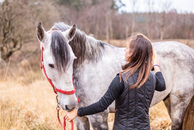 Rear view of woman riding horse on field