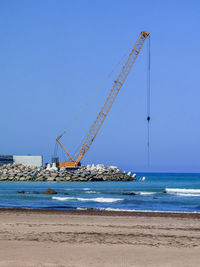 Heavy metallic machine moving rocks on the ocean in order to create a wall for the new port