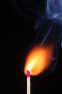 Close-up of lit candle against black background