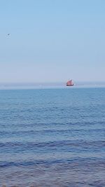 Boat sailing on sea against clear sky