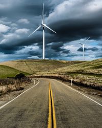 Windmill on road against sky