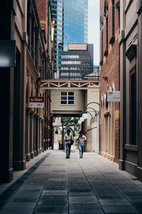 Rear view of people walking on street amidst buildings