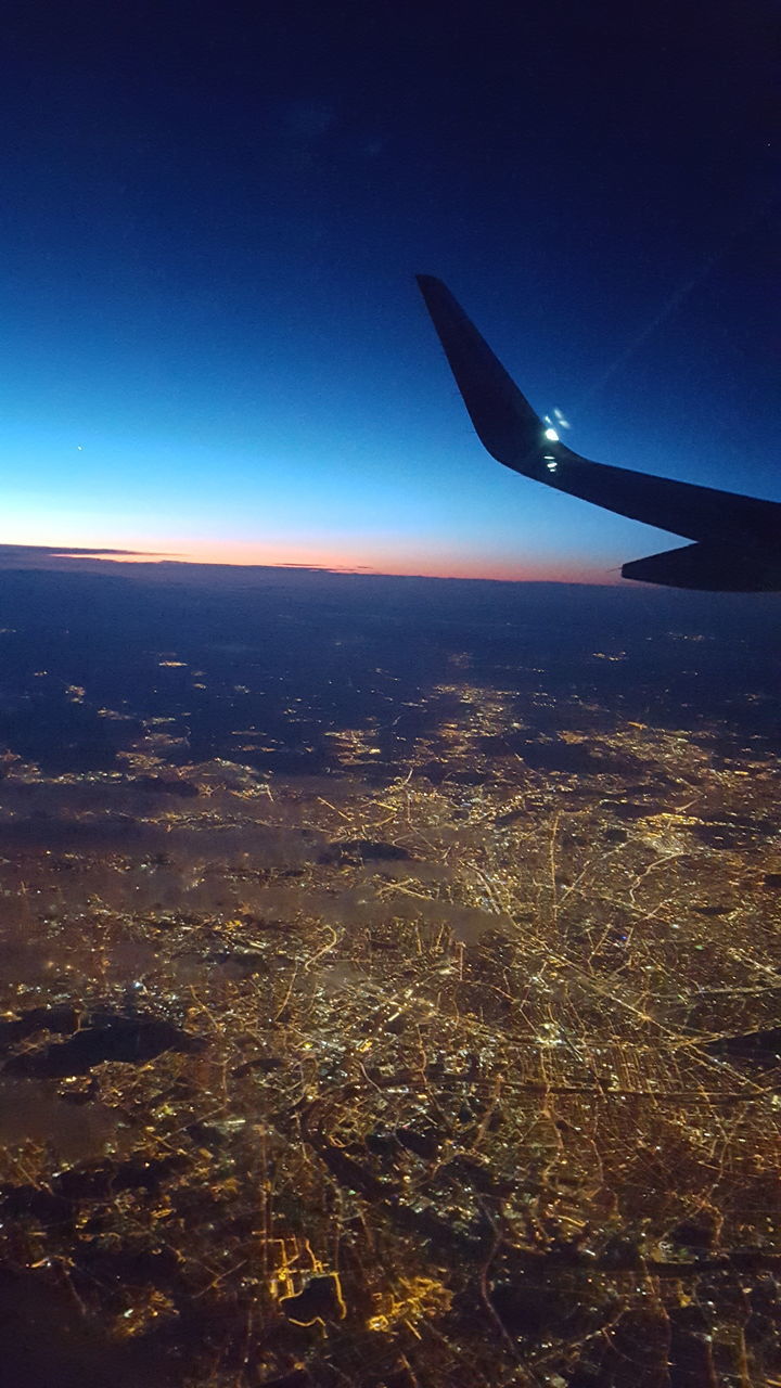 flying, airplane, air vehicle, blue, aircraft wing, clear sky, mode of transport, part of, transportation, illuminated, aerial view, city, cityscape, journey, mid-air, sky, scenics, wing, outdoors, nature, horizon, majestic, airplane wing, horizon over land, mid air, mountain, no people, animal wing