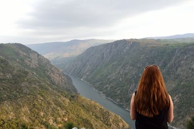 Rear view of woman standing on mountain against sky