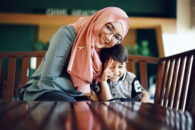 Portrait of mother smiling while sitting with son at table
