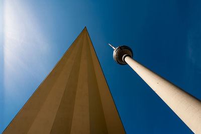 Low angle view of communications tower and building against blue sky