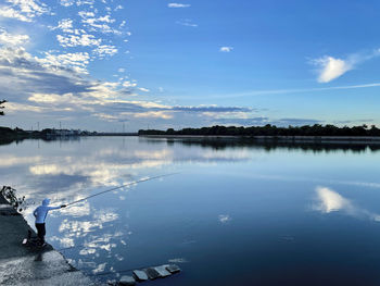 Reflection of man standing in lake against sky