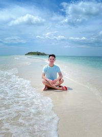 Portrait of woman sitting on beach against sky