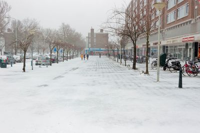 Snow covered street amidst buildings in city