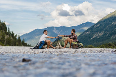 People sitting on mountain against sky