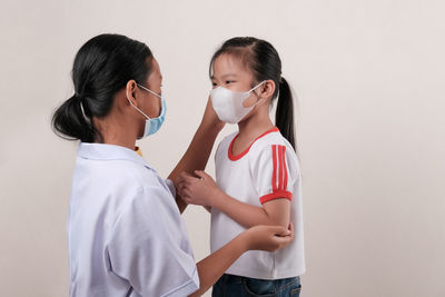 Side view of two women standing against white background