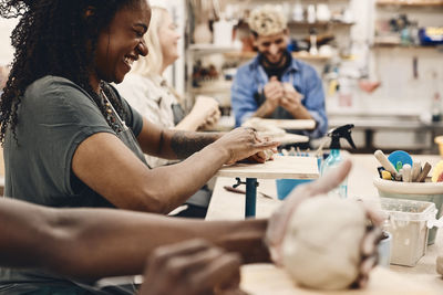 Cheerful mature woman molding clay while practicing in art class