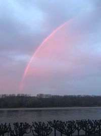 Scenic view of rainbow over lake against sky