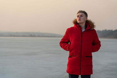 Young woman standing by red against sky during sunset