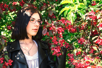 Portrait of beautiful young woman standing by flowering plants