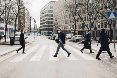 Business people crossing street in city during pandemic