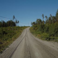 Road amidst trees against clear sky