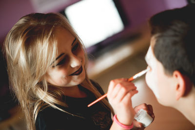 Girl doing face paint on brother at home during halloween