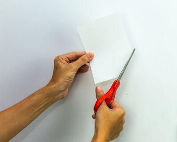 Close-up of hand holding paper against white background