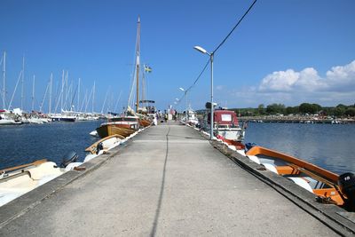 Sailboats moored on harbor in city against sky