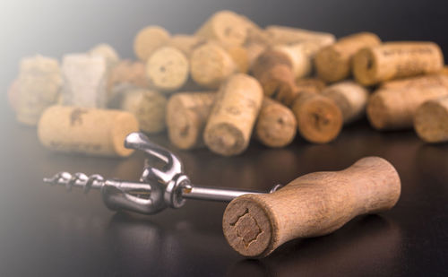 Wine corks and corkscrew on black wooden table in soft sunlight